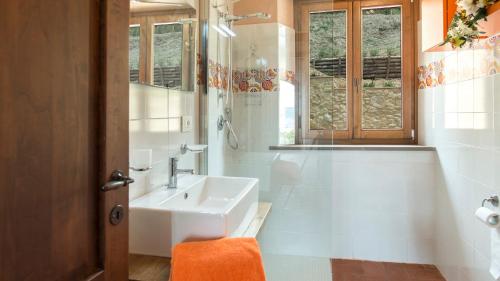 uma casa de banho branca com um lavatório e uma janela em La Vecchia Fonte 15, Emma Villas em Volterra