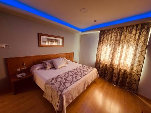 a bedroom with a bed with a blue ceiling at Hotel Cies in Calvarrasa de Abajo