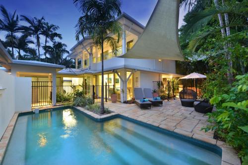 a house with a swimming pool in front of a house at Reef Villa Port Douglas in Port Douglas