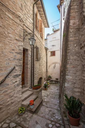 an alley in an old stone building with flowers at Perla in Spello