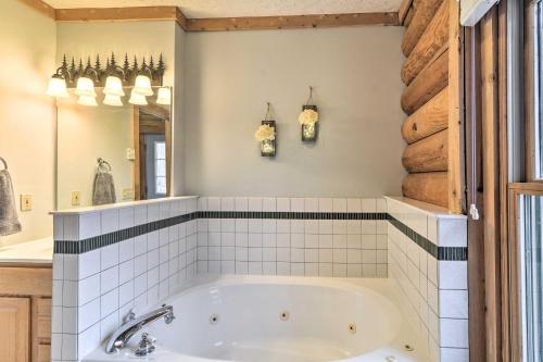 a bathroom with a tub and a mirror at Secluded Gaylord Cabin with Deck, Fire Pit and Grill! in Gaylord