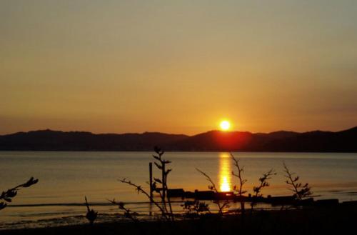 a sunset over a body of water with a boat at 83 By The Sea Motor Lodge in Lower Hutt