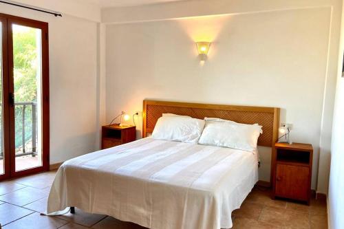 a bedroom with a bed with white sheets and a window at Sunrise Apartment 20 in San Pantaleo