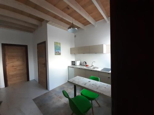 a kitchen with a table and some green chairs at Apartamenty Róża Wiatrów in Solec-Zdrój