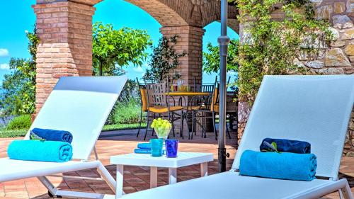 two white chairs on a patio with a table at Villa Bella 8, Emma Villas in Massa Martana