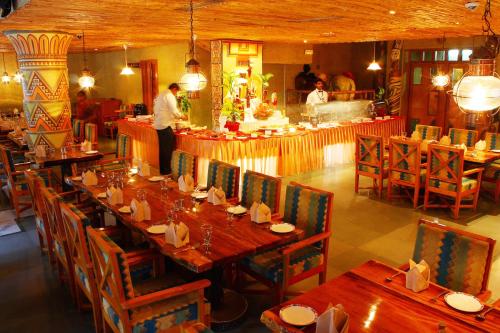 a restaurant with tables and chairs and a chef in the kitchen at Ramoji Film City- Tara Comfort Hotel in Pedda Ambarpet