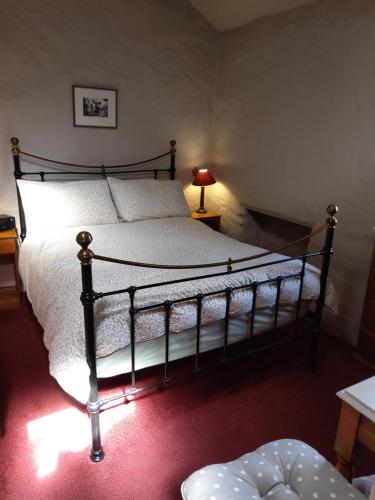 um quarto com uma cama grande com lençóis brancos e um candeeiro em Lile Cottage at Gleaston Water Mill em Ulverston