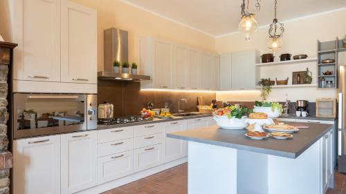 a kitchen with white cabinets and a black counter top at Villa Fiorentini 10, Emma Villas in Barberino di Val dʼElsa