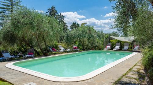 a swimming pool in a yard with chairs and trees at Villa Fiorentini 10, Emma Villas in Barberino di Val dʼElsa