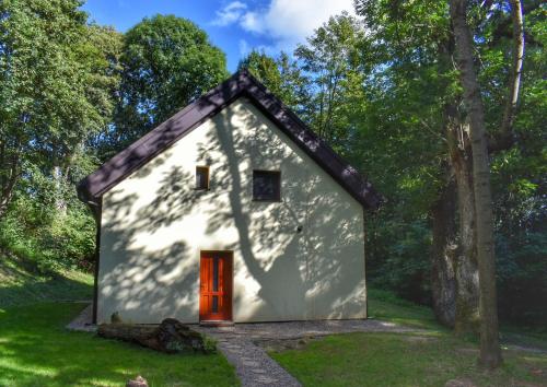 a small white house with a red door in a forest at Cottage Refresh in Banská Štiavnica