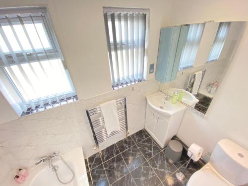 a bathroom with a sink and a toilet and a mirror at Airport Comfy Stay in Harmondsworth