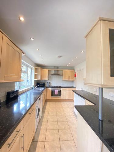 a large kitchen with wooden cabinets and black counter tops at Airport Comfy Stay in Harmondsworth