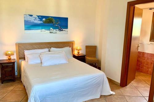 a bedroom with a large white bed with two tables at Sunrise 23 in San Pantaleo