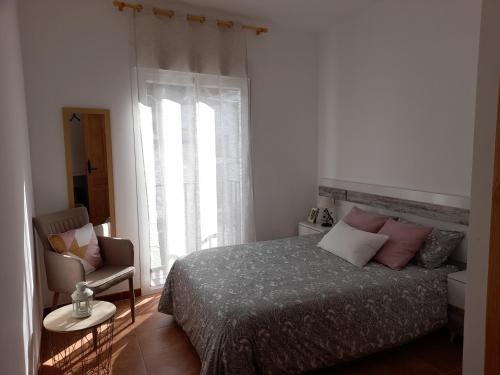 a bedroom with a bed and a chair and a window at APARTAMENTO ESTACIÓN 54 in Benaoján