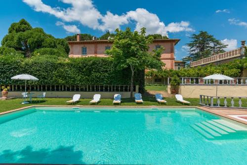 una piscina con sillas y una casa en el fondo en VILLA DELLE SOPHORE 16&4, Emma Villas en Cortona