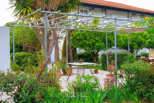 una pérgola con una mesa en un jardín en Zante Apts, en Laganas