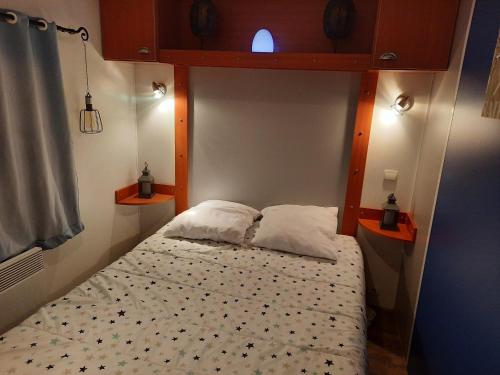 Cama en habitación pequeña con 2 almohadas en Location mobil home, en La Baule