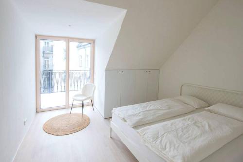 - une chambre avec un lit, une chaise et une fenêtre dans l'établissement STILVOLL und LUFTIG IM HERZEN VON LINZ, à Linz