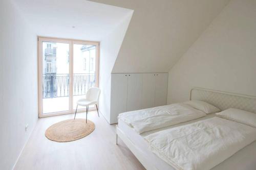 a bedroom with a bed and a chair and a window at STILVOLL und LUFTIG IM HERZEN VON LINZ in Linz