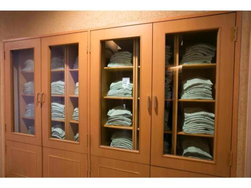 a wooden cabinet with glass doors with towels at R&B Hotel Nagoya Nishiki - Vacation STAY 15170v in Nagoya