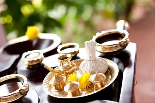 a table topped with gold and white vases on a plate at Gateway Coonoor in Coonoor