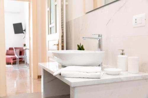 Un baño blanco con lavabo y toallas en una encimera. en Ecalù Siracusa, en Siracusa