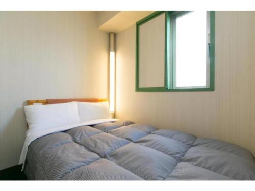 a bed in the corner of a room with a mirror at R&B Hotel Nagoya Nishiki - Vacation STAY 15171v in Nagoya