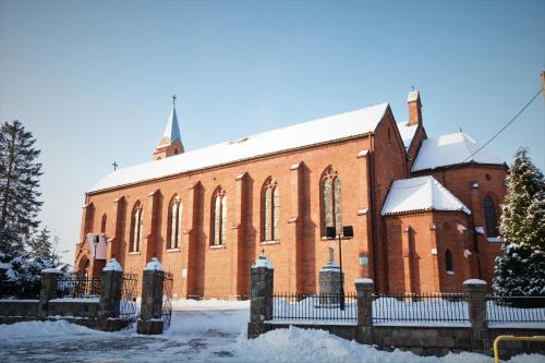 a large red brick church with a snow covered roof at Baza Lipusz jacuzzi in Lipusz