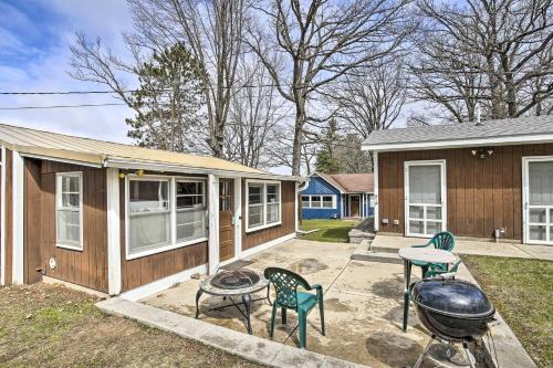 a house with a grill and chairs in a yard at Lakefront 1930s Log Cabin with Dock and Fire Pit! in Rice Lake