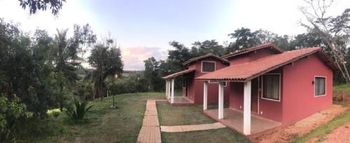 a small red house in a field with trees at Chalés do Recanto in São João del Rei