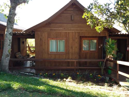 a log cabin with a porch and a tree at Pousada Vó Liane in Praia Grande