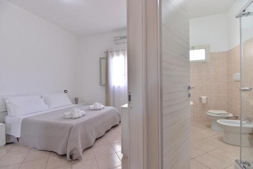 ein weißes Schlafzimmer mit einem Bett und einem Badezimmer in der Unterkunft IzzHome Lagoon in Pula