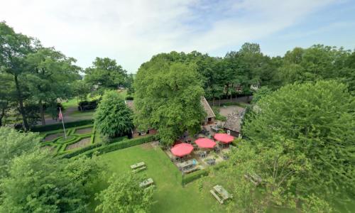 una vista aérea de una casa con sombrillas rojas en Hotel Boerderij Restaurant De Gloepe en Diffelen