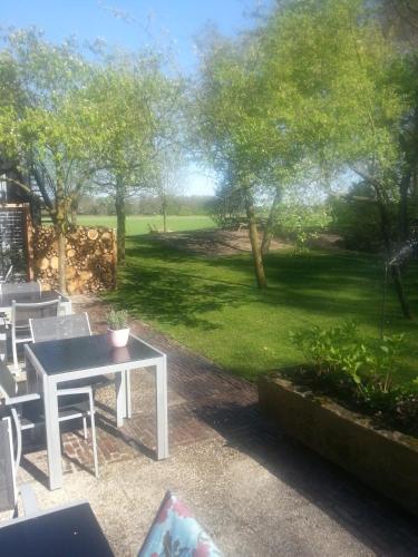 a patio with a table and chairs and a green field at Hotel Boerderij Restaurant De Gloepe in Diffelen