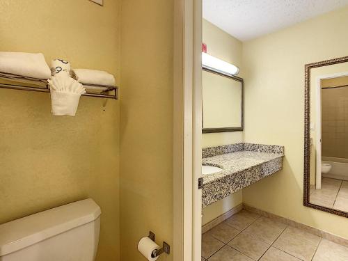 a bathroom with a toilet and a sink and a mirror at Stayable Orlando at Florida Mall in Orlando