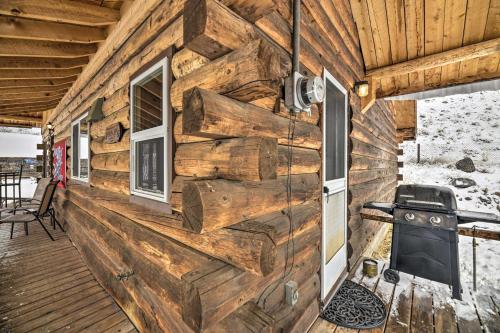 a wall of a log cabin with a door and a grill at Cozy Log Cabin Escape In the Heart of Creede! in Creede
