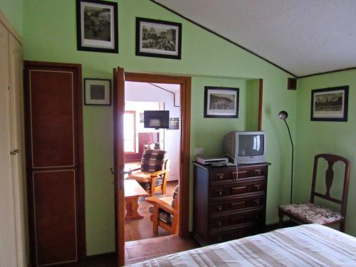 a bedroom with green walls and a bed and a television at Casa Emanuela 1 in Baiardo