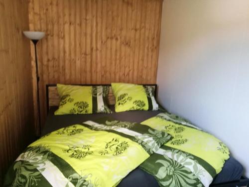 a bed with yellow and green sheets and pillows at WUDINO - Ubytování v přírodě, se zvířaty v industriálním duchu, in Ostrov u Macochy