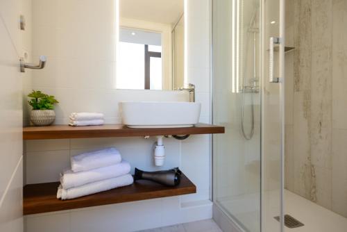 een badkamer met een wastafel en een douche met handdoeken bij Apartamentos enfrente del Museo Dalí in Figueres