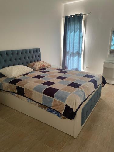 a bed with a checkered blanket and a window at شاليه أرضي بجنينه في مارينا وادي دجله العين السخنه Three Bedroom Chalet with Garden In Marina Wadi Degla Ain El Sokhna - For Families Only in Ain Sokhna