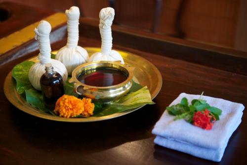 a plate with a bowl of syrup and flowers on a table at The Gateway Hotel Beach Road, Calicut in Kozhikode