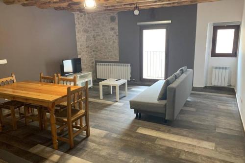 ein Wohnzimmer mit einem Tisch, einem Sofa und einem TV in der Unterkunft Apartamento Rural Casa Bergua en Arguis in Arguis