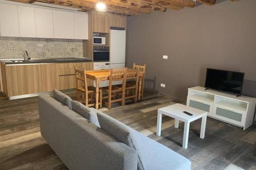 ein Wohnzimmer mit einem Sofa und einem Tisch sowie eine Küche in der Unterkunft Apartamento Rural Casa Bergua en Arguis in Arguis
