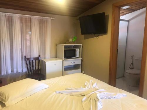a bedroom with a bed with a microwave and a television at Apartamentos Sulla Collina Centro de Gramado localizado próximo da rua Coberta in Gramado