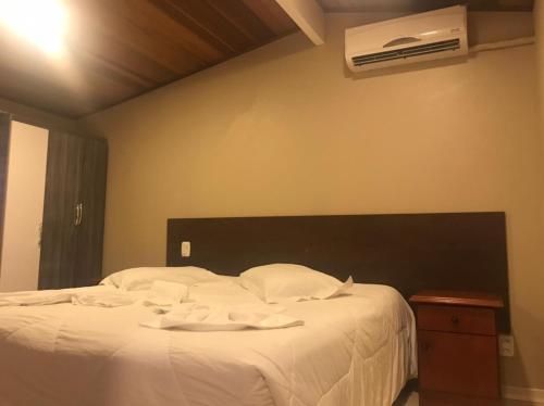 a bedroom with a bed with white sheets and a fan at Apartamentos Sulla Collina Centro de Gramado localizado próximo da rua Coberta in Gramado