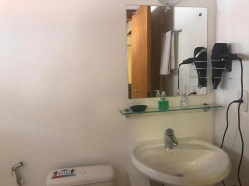 a bathroom with a sink and a mirror and a toilet at Apartamentos Sulla Collina Centro de Gramado localizado próximo da rua Coberta in Gramado