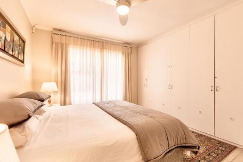 a white bedroom with a bed and a window at Perlemoen Retreat in Herolds Bay