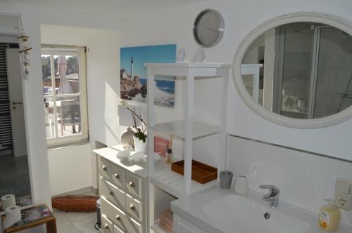 ein weißes Badezimmer mit einem Waschbecken und einem Spiegel in der Unterkunft Apartment anno 1720 in Quedlinburg