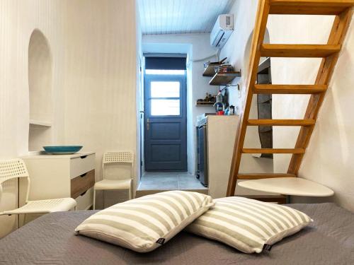 a bed with a pillow in a room with a ladder at Bougainvillea Friends & Family Studio - Old Town in Mikonos