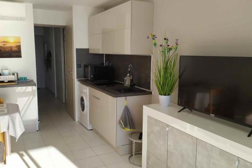Il comprend une cuisine avec des placards blancs, un évier et une télévision. dans l'établissement Nice Apartment With Sea View And Balcony, à Cannes